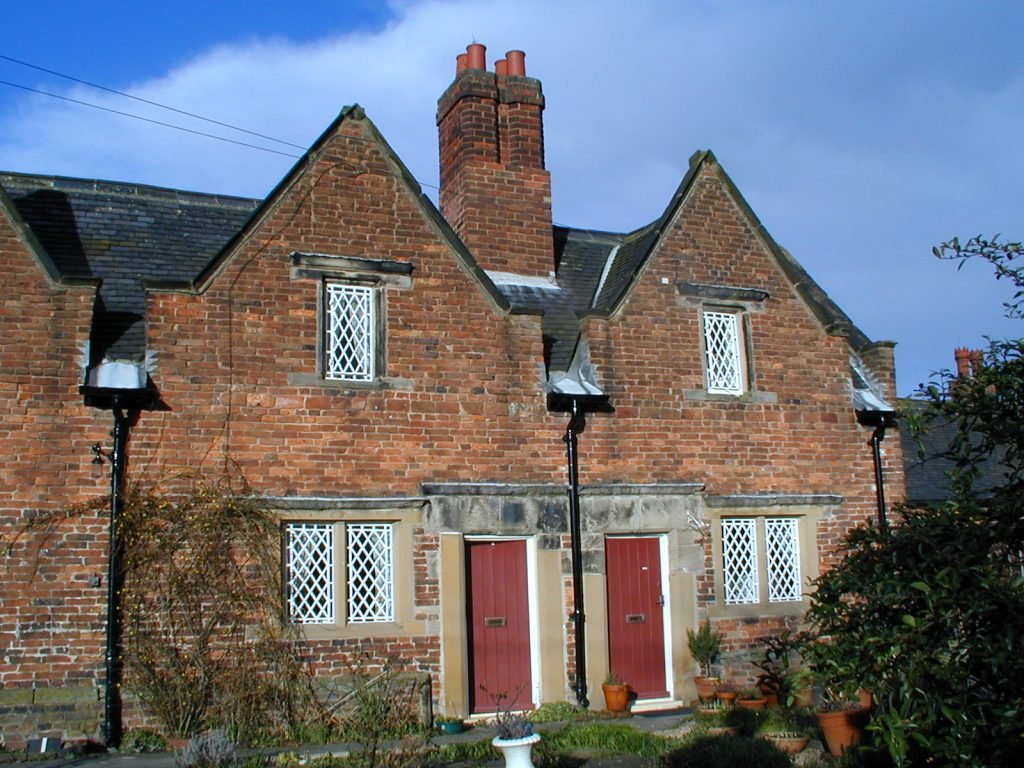 Almshouses with triangular rooves, a chimney and red doors