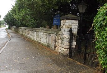 white stone wall leading to black gate