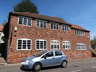 red brick building with white windows, car in front