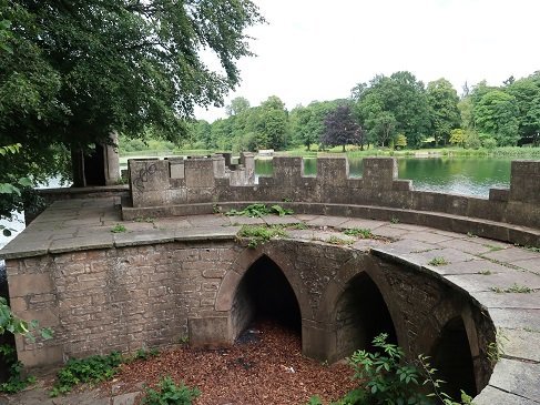 arches below walkway with castle-like top, body of water beyond