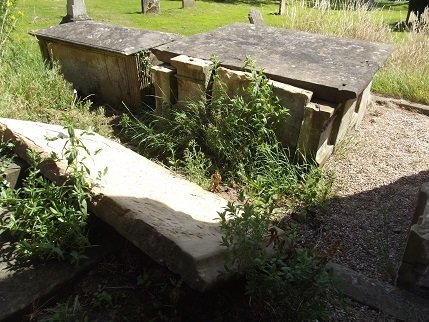 white slab in front of two tombs with some weeds