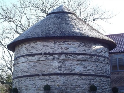 Thoroton Dovecote - a round white/grey building with a thatched roof
