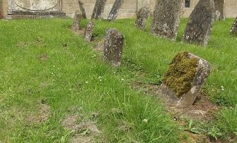 row of five small rounded headstones in grass