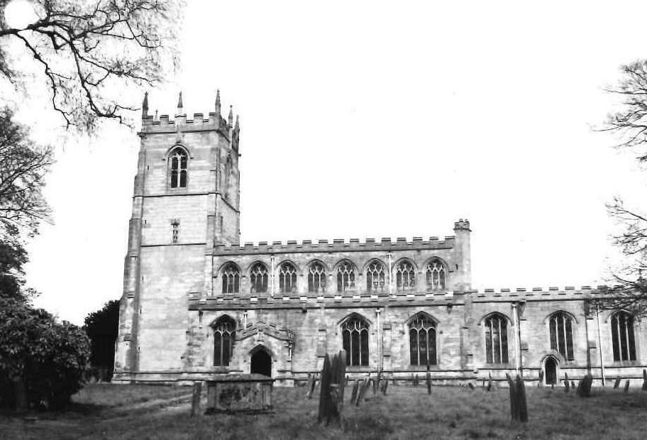 black and white photo of side of church with two stories and square tower on left