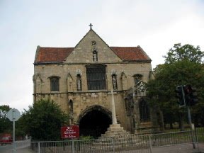 brown building with red roof and cross outside of archway