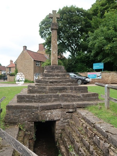 stone cross with stepped base and stairs to door below