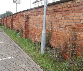 red brick wall with buttresses, lamppost in front