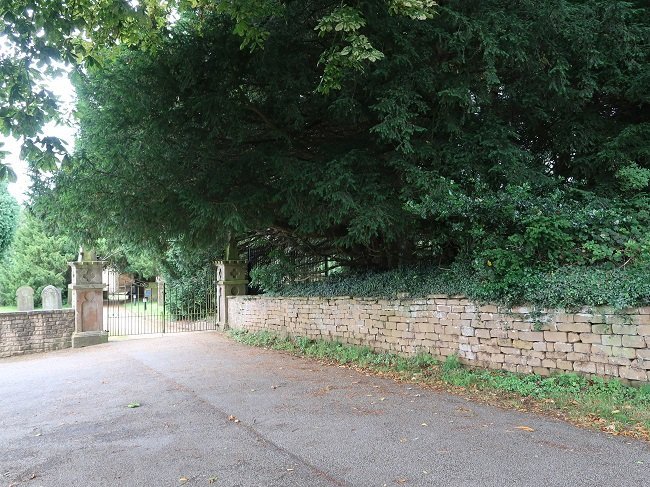 wall leading to gate. trees behind